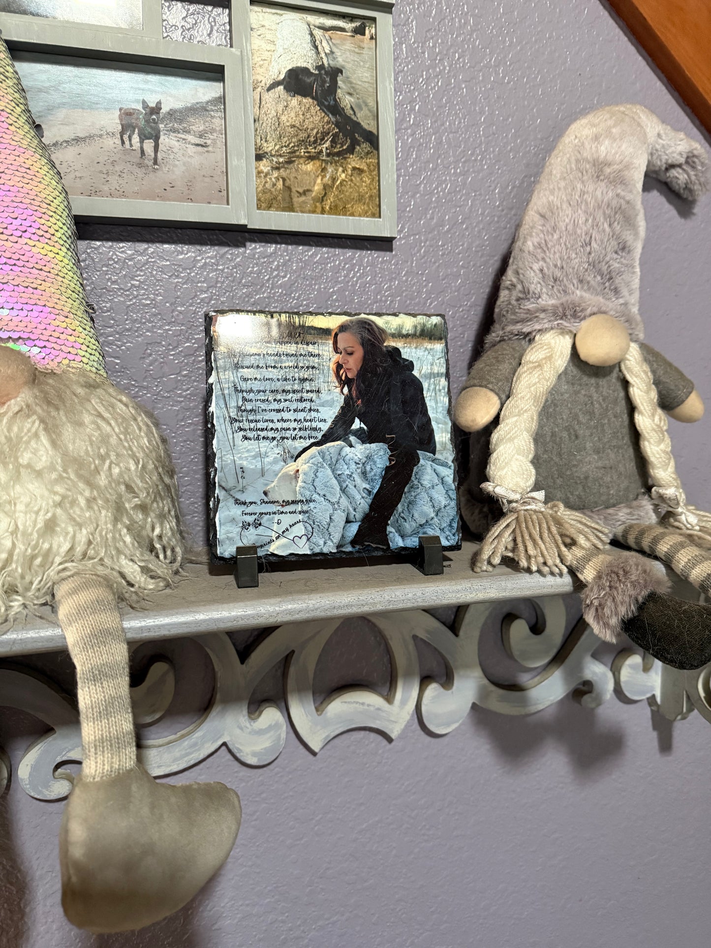 Decorative shelf with gnomes and a framed picture of a person sitting on steps.