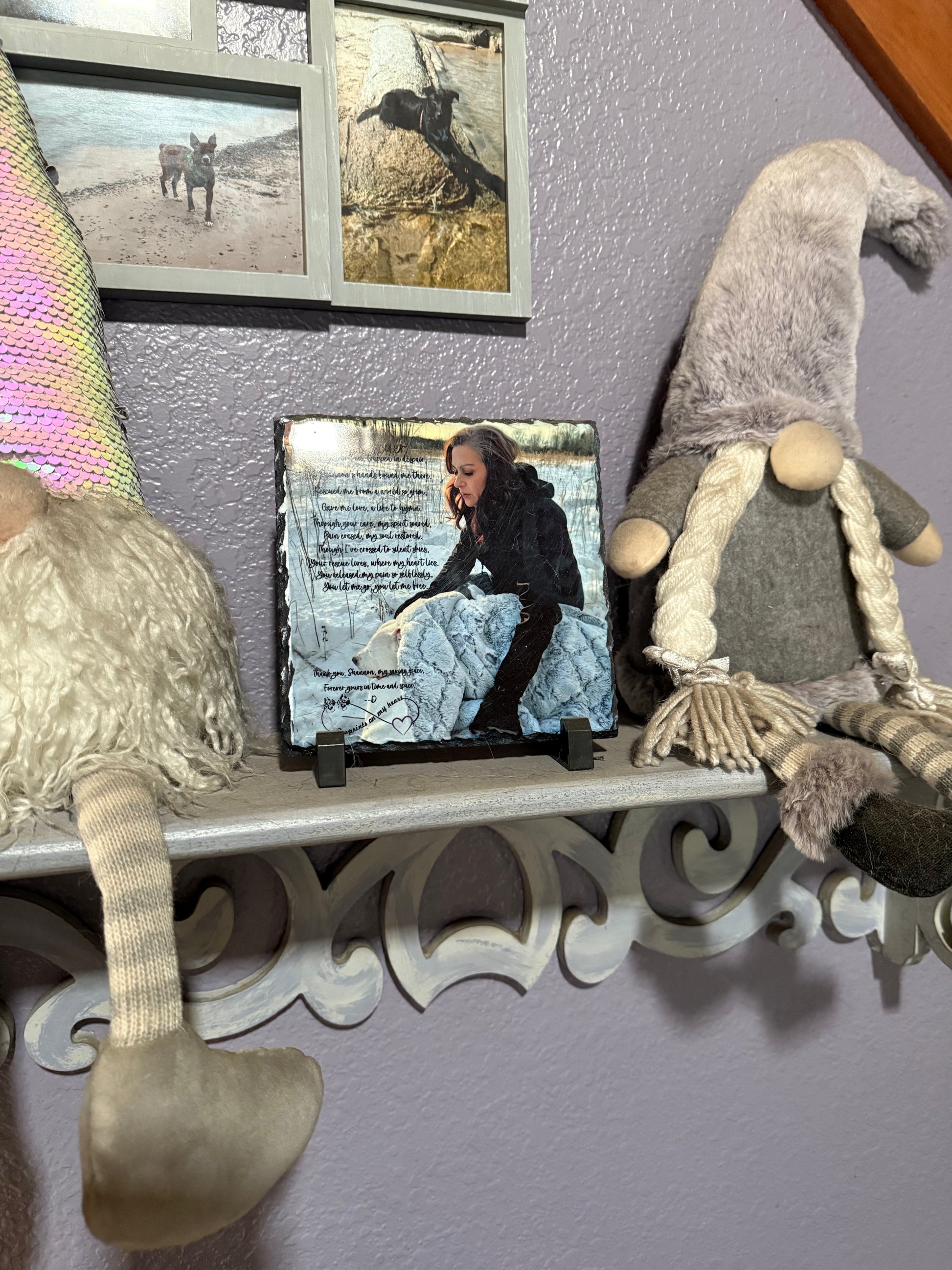 Decorative shelf with gnomes and a framed picture of a person sitting on steps.