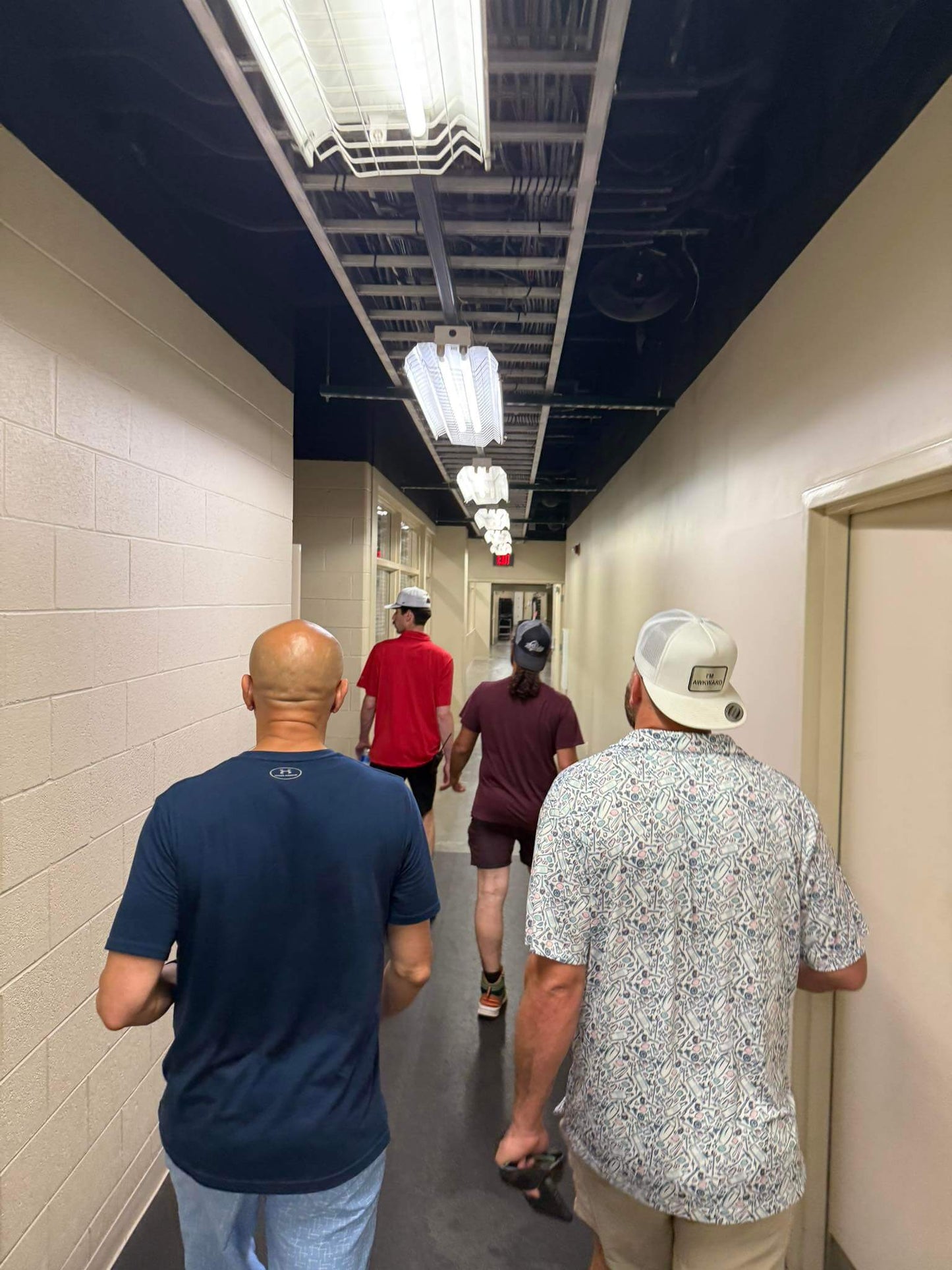 White mesh back trucker hat worn by a person walking in a hallway with others