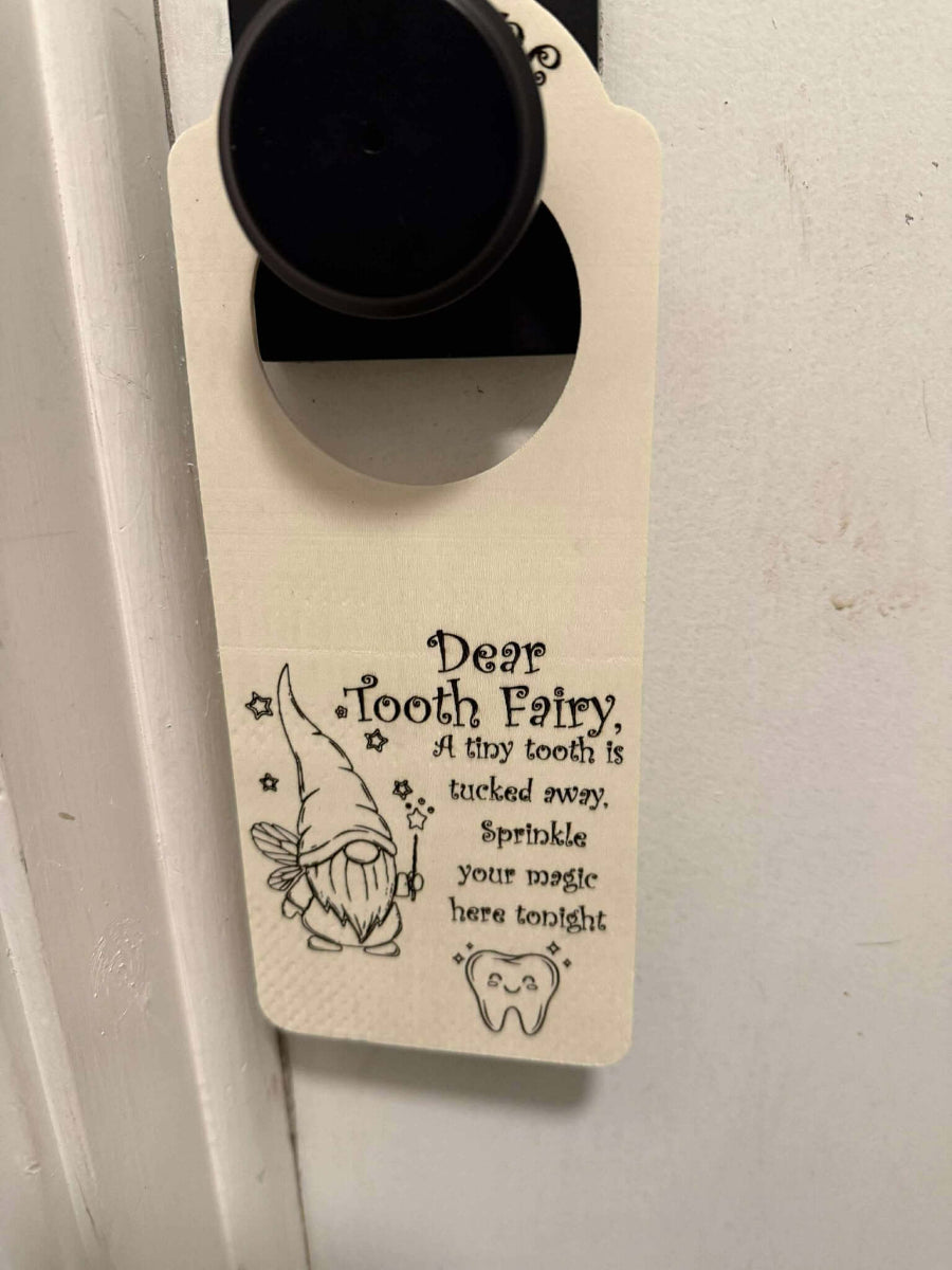 Personalized wooden tooth fairy door hanger hanging on a door, featuring engraved gnome fairy and smiling tooth design with a message for the tooth fairy.